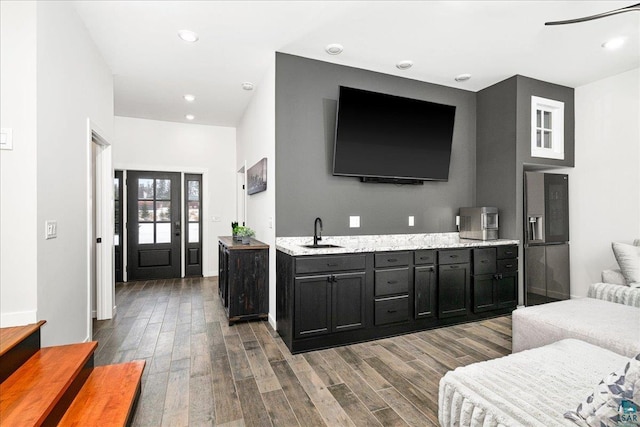 interior space featuring sink, stainless steel refrigerator with ice dispenser, and light stone counters