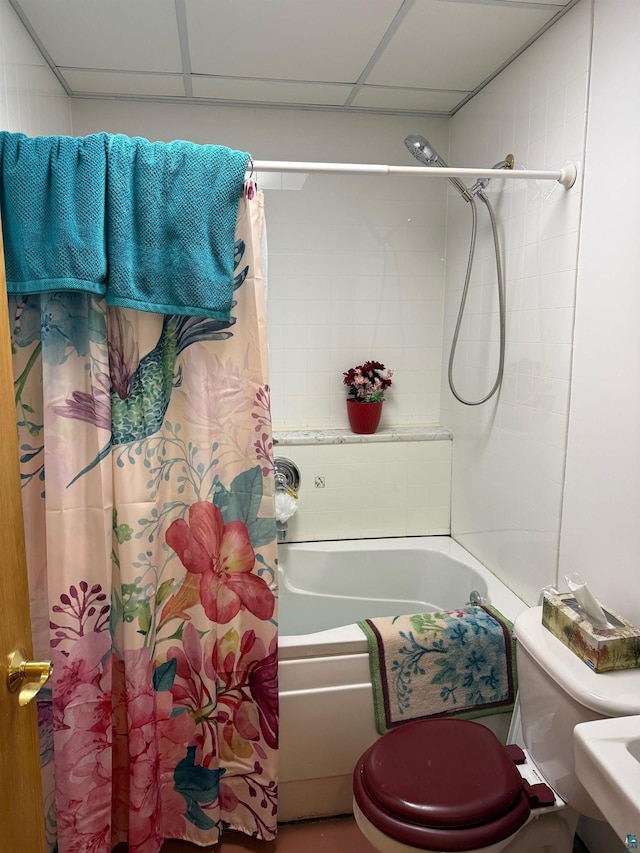 bathroom with shower / tub combo, a paneled ceiling, and toilet