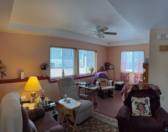 living room featuring a raised ceiling and ceiling fan