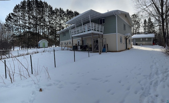 snow covered back of property featuring a storage unit