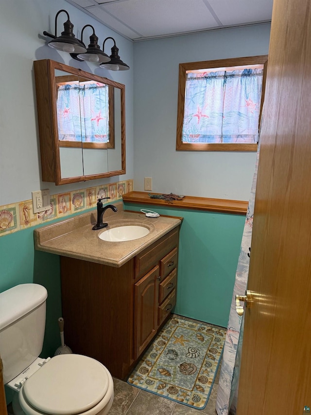 bathroom with tile patterned floors, vanity, toilet, and a paneled ceiling