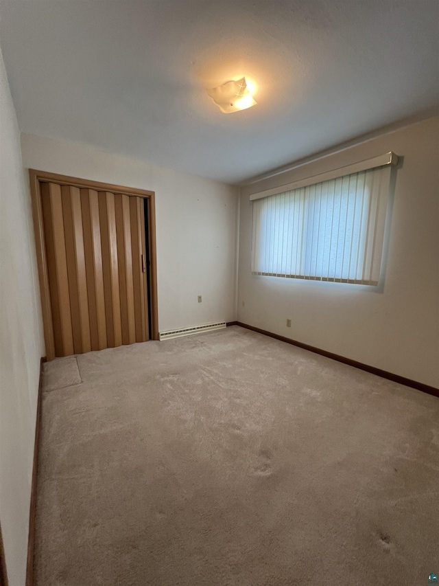 carpeted empty room featuring baseboard heating