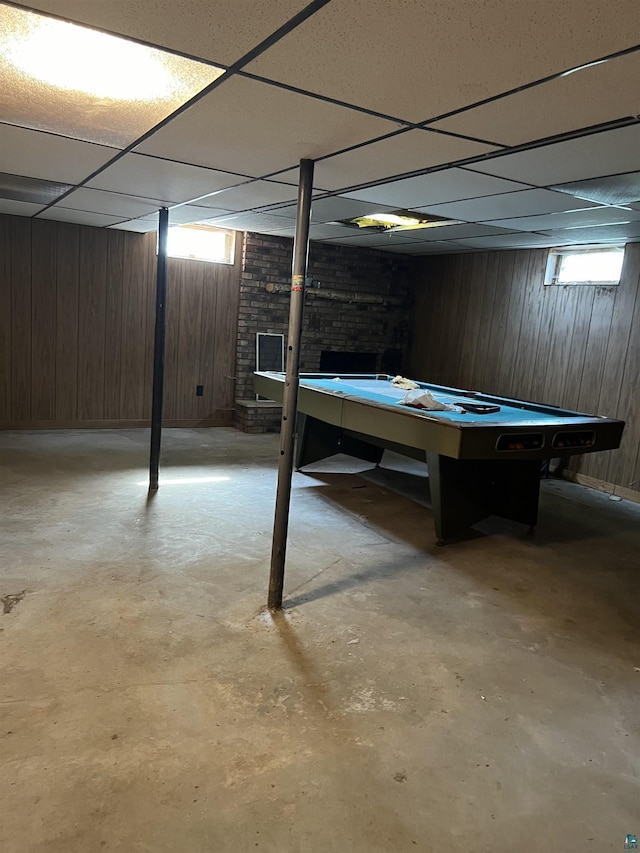 basement with a paneled ceiling and wood walls