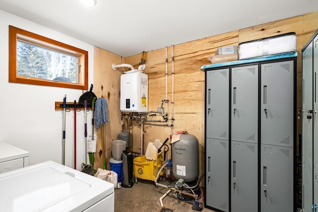 clothes washing area featuring water heater, washing machine and clothes dryer, and wooden walls