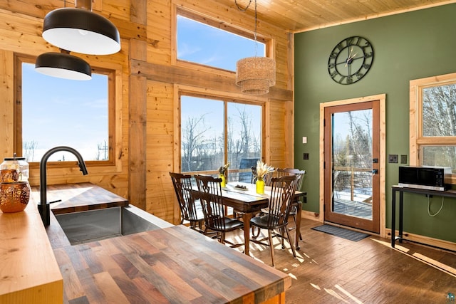 dining room featuring sink, wood ceiling, wooden walls, and dark wood-type flooring