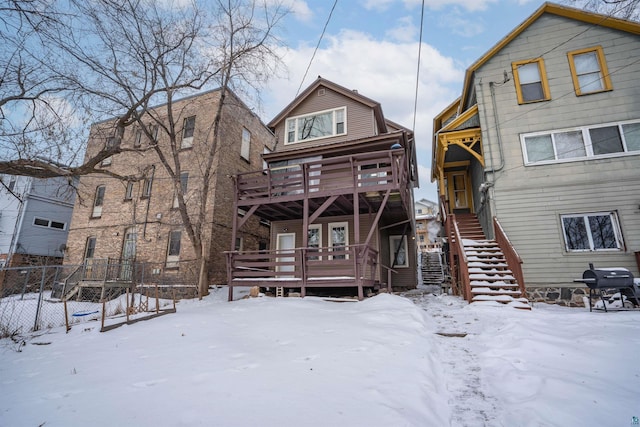 snow covered back of property with a deck