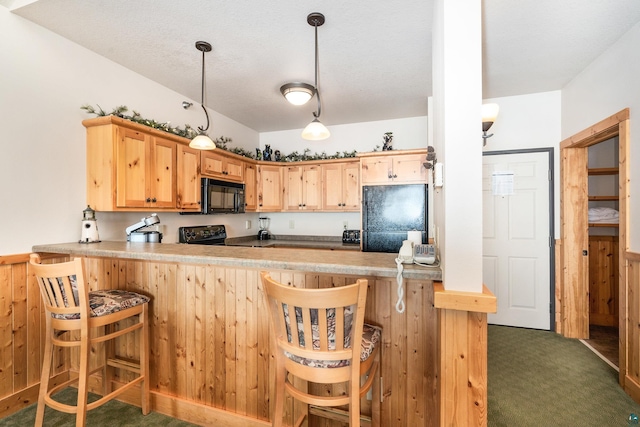 kitchen with pendant lighting, wooden walls, black appliances, dark carpet, and kitchen peninsula