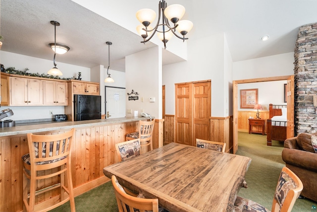 carpeted dining room featuring a chandelier, a textured ceiling, and wooden walls