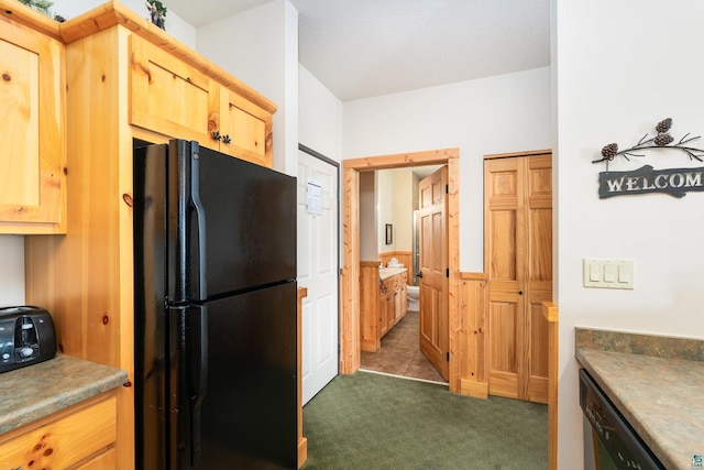 kitchen with light brown cabinetry, dark carpet, and black appliances