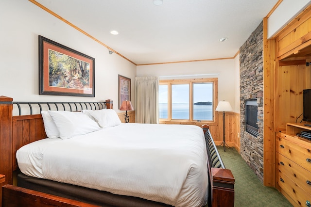 carpeted bedroom featuring crown molding and a stone fireplace