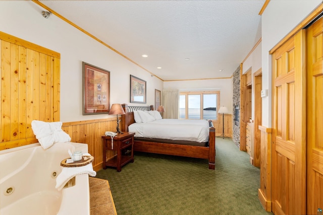 bedroom featuring wood walls, ornamental molding, a textured ceiling, and dark colored carpet