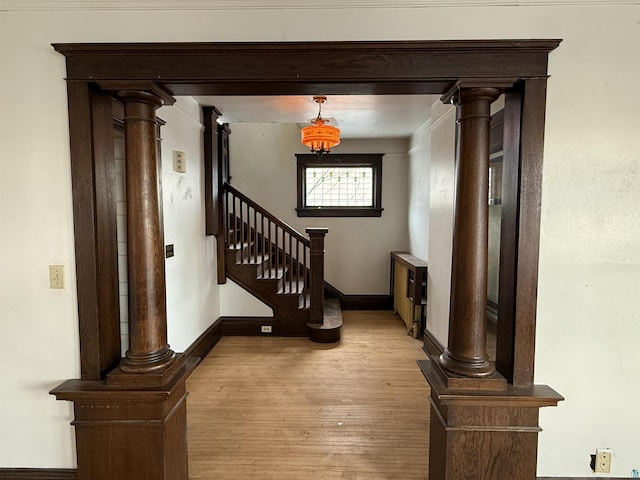 interior space featuring crown molding, decorative columns, and light hardwood / wood-style floors