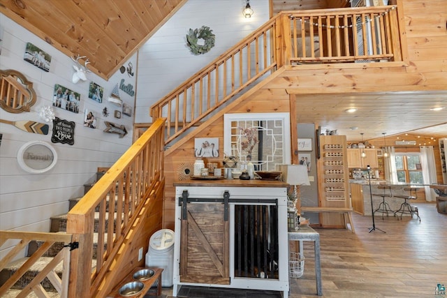 staircase with wood ceiling, wooden walls, hardwood / wood-style floors, and vaulted ceiling