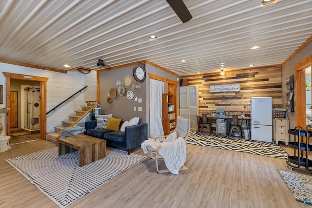 living room with light hardwood / wood-style flooring and wood walls