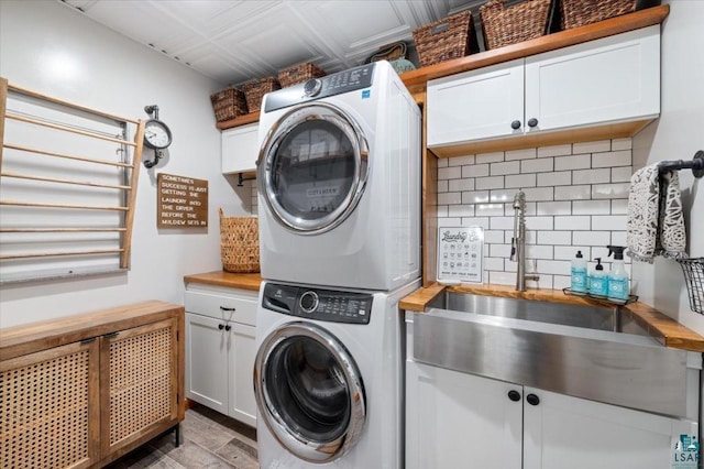 laundry room featuring sink, cabinets, and stacked washing maching and dryer