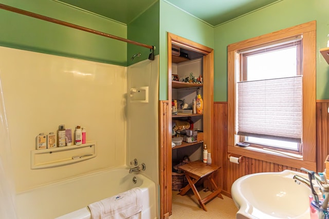 bathroom with a healthy amount of sunlight, sink, and wood walls