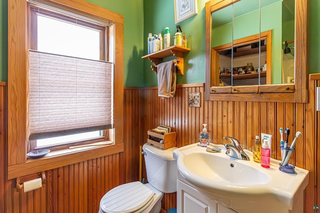 bathroom featuring vanity, a wealth of natural light, wooden walls, and toilet