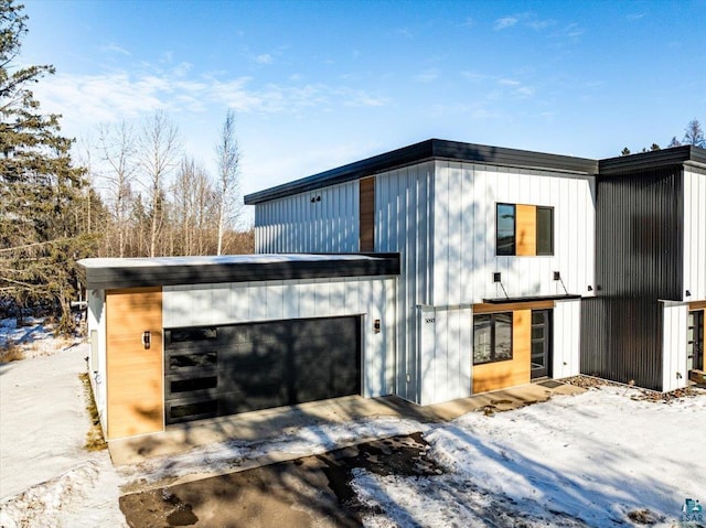 snow covered property with a garage