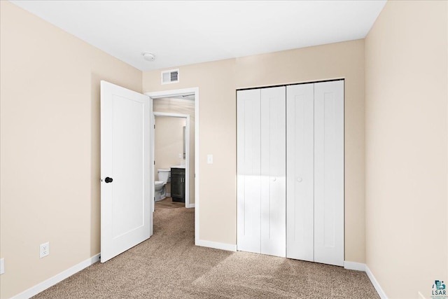 unfurnished bedroom featuring light colored carpet and a closet