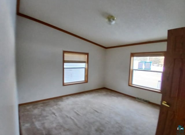 empty room with carpet floors, vaulted ceiling, and ornamental molding