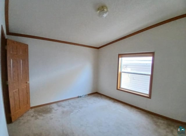 carpeted spare room featuring ornamental molding and vaulted ceiling