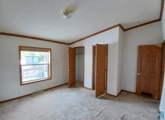 unfurnished bedroom featuring lofted ceiling, light colored carpet, and ornamental molding