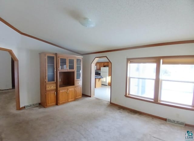 unfurnished living room with crown molding, vaulted ceiling, and light colored carpet