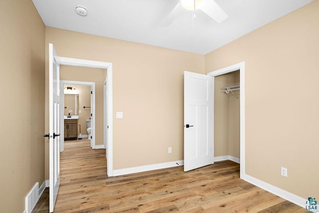 unfurnished bedroom featuring a closet, sink, ceiling fan, and light hardwood / wood-style flooring