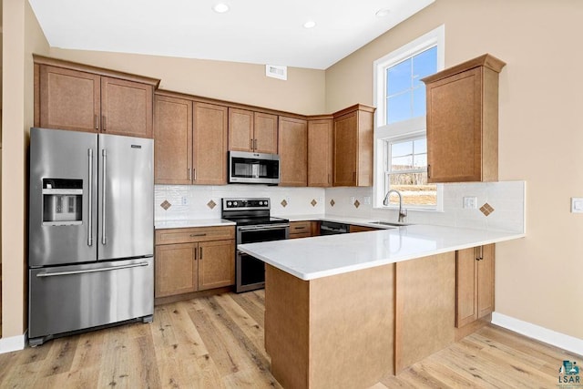 kitchen with tasteful backsplash, appliances with stainless steel finishes, kitchen peninsula, and sink