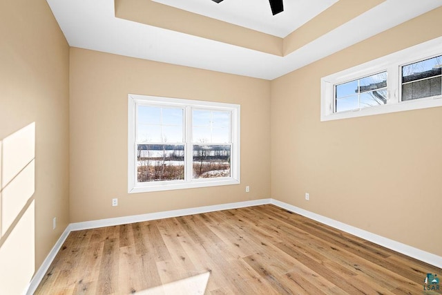 empty room featuring light hardwood / wood-style floors, a raised ceiling, and ceiling fan