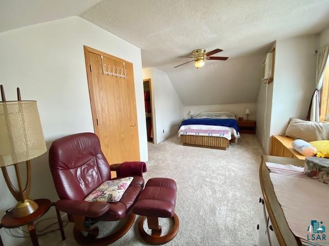 bedroom featuring lofted ceiling, carpet floors, a textured ceiling, and a closet