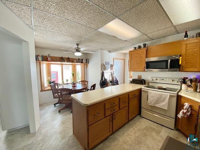 kitchen featuring a drop ceiling, kitchen peninsula, ceiling fan, and white range with electric cooktop