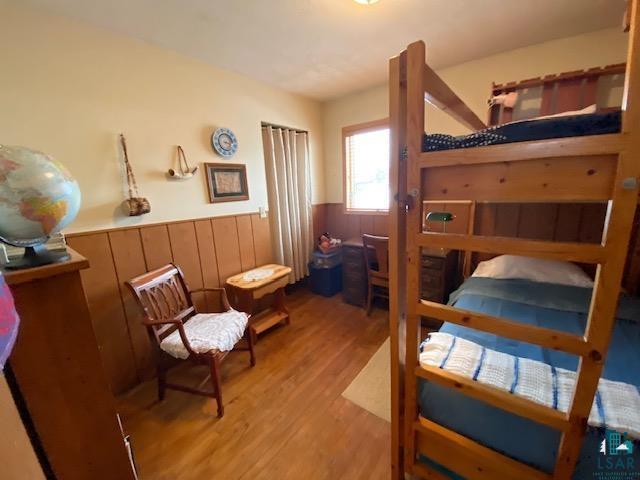 bedroom featuring light hardwood / wood-style flooring and wood walls