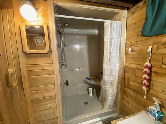 bathroom featuring a shower with shower curtain and wood walls