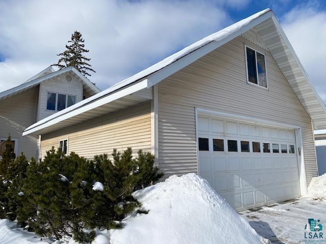 snow covered property with a garage