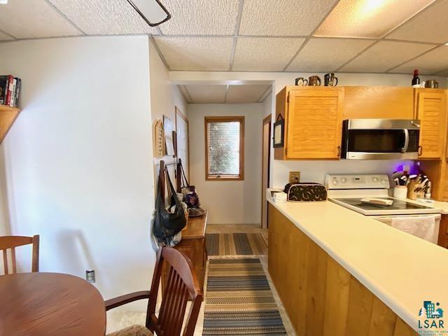 kitchen with a paneled ceiling and white electric range