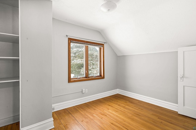 bonus room featuring lofted ceiling, hardwood / wood-style floors, and a textured ceiling