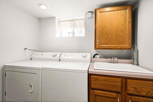 washroom with cabinets, sink, washing machine and clothes dryer, and a textured ceiling