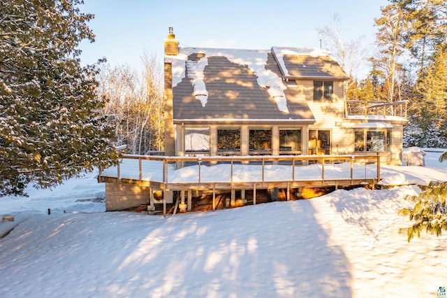 snow covered rear of property with a wooden deck