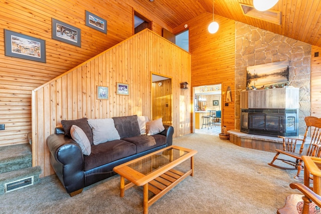 living room featuring wood walls, wood ceiling, high vaulted ceiling, a fireplace, and carpet