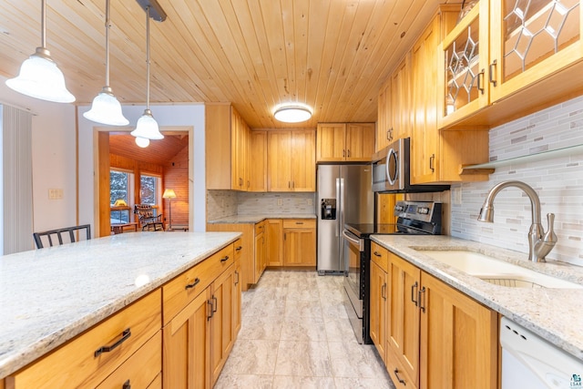 kitchen with light stone counters, sink, hanging light fixtures, and appliances with stainless steel finishes