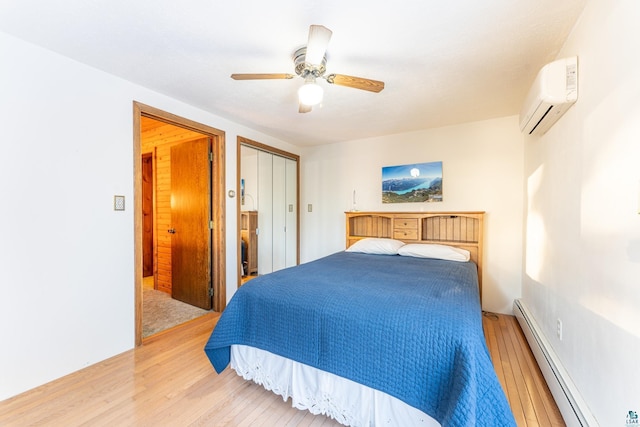 bedroom featuring hardwood / wood-style flooring, ceiling fan, an AC wall unit, a baseboard radiator, and a closet