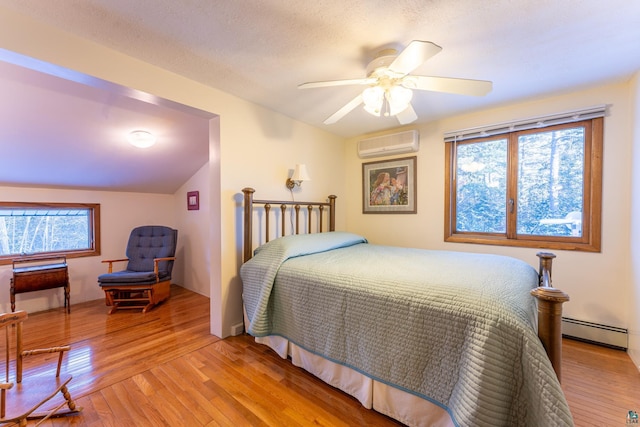 bedroom featuring baseboard heating, a wall mounted air conditioner, light hardwood / wood-style floors, and multiple windows