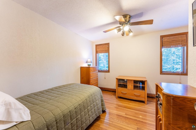 bedroom with ceiling fan, light hardwood / wood-style floors, and a textured ceiling