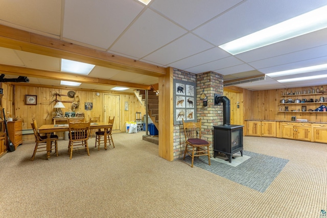 interior space with wooden walls, a paneled ceiling, and a wood stove