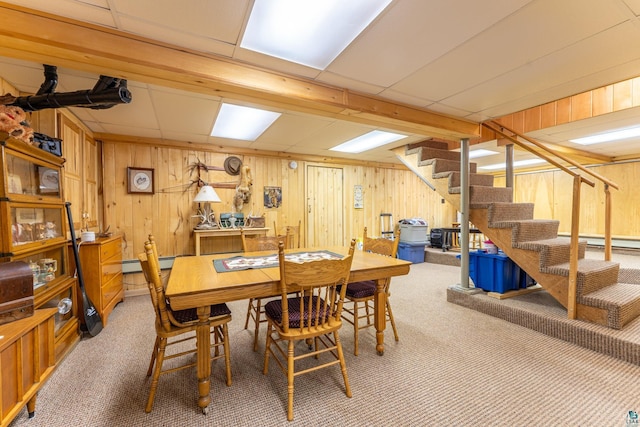 dining room featuring wooden walls, a paneled ceiling, and carpet