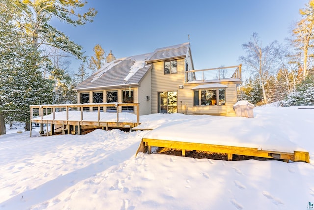 snow covered rear of property featuring a balcony and a deck