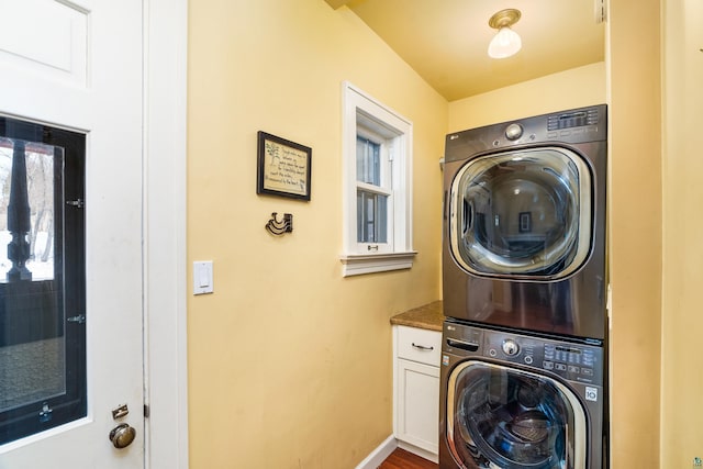 clothes washing area featuring cabinets and stacked washer / drying machine