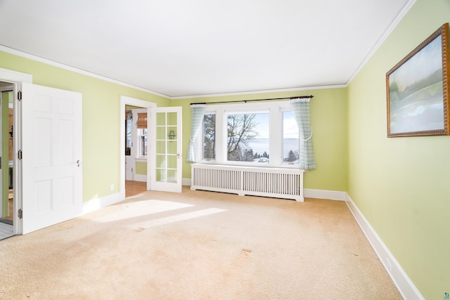 spare room with radiator, carpet floors, ornamental molding, and french doors