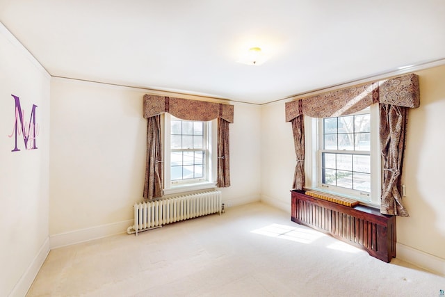 carpeted empty room with ornamental molding, plenty of natural light, and radiator heating unit